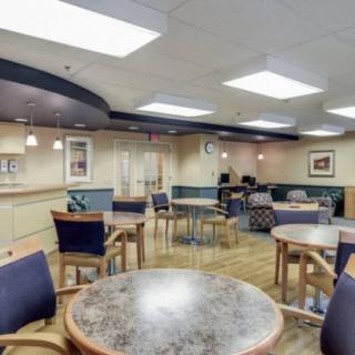 A spacious waiting area with tables and chairs under bright ceiling lights.