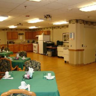 An indoor dining area with tables and chairs, adjacent to a kitchen.