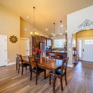 A modern dining area with an open kitchen, featuring wood floors and stylish lighting.