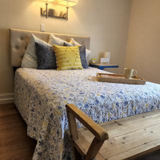 A cozy bedroom setup featuring a beautifully made bed with decorative pillows and a wooden table.