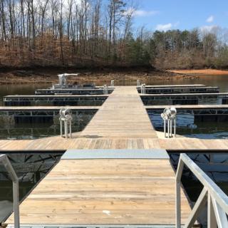 A wooden dock extending over a calm lake under a clear sky.