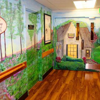 A hallway with a vibrant mural depicting a nature scene and a quaint house.