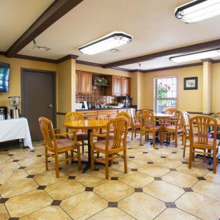 A cozy dining area with wooden tables and chairs, adjacent to a small kitchen.