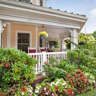 A charming front porch adorned with vibrant flowers and comfortable rocking chairs, creating a welcoming atmosphere.