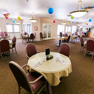 A festive dining area decorated with colorful balloons and set tables.