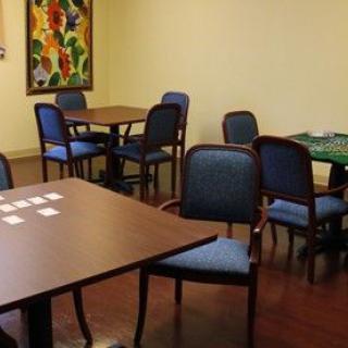 A room with multiple tables and chairs, featuring a colorful painting on the wall.