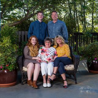 A family group portrait taken outdoors in a garden setting.