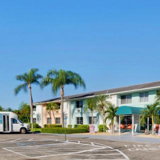 A sunny day at a hotel with palm trees and a bus parked in front.