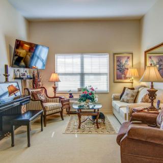 A cozy living room with elegant furnishings and decor, featuring a piano and ample lighting.