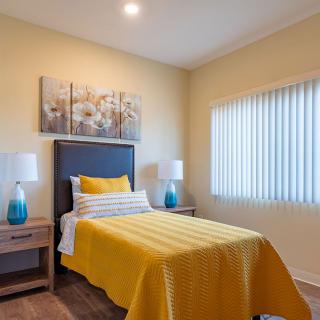 A modern bedroom with a single bed featuring yellow bedding and stylish decor.