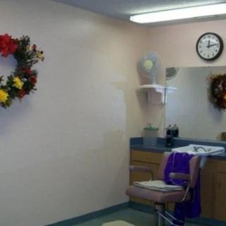 A cozy barber shop interior with a mirror, chair, and decorative wreaths on the wall.