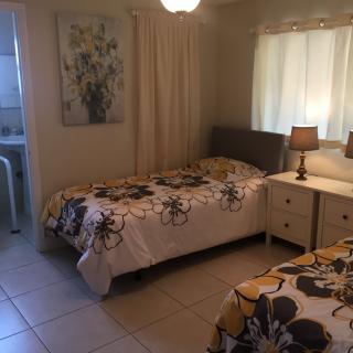 A cozy bedroom featuring two single beds with floral bedding, a nightstand with a lamp, and wall art.