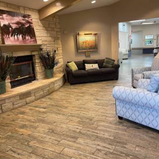 A cozy living room with a fireplace and comfortable seating, featuring decorative artwork on the walls.