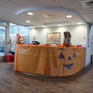 A Halloween-themed reception area decorated with orange drapes and pumpkin cutouts.