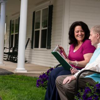 Two people sitting on a patio, enjoying a conversation while reading together.