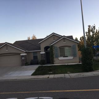 A suburban house with a well-maintained lawn and driveway, located on a quiet street.