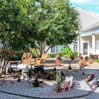 A beautifully landscaped garden featuring comfortable seating, greenery, and decorative elements.