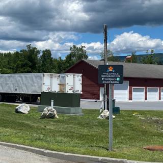 A view of a red building with storage units, set against a cloudy sky.