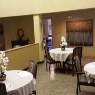 A cozy dining area with neatly arranged tables and chairs, adorned with elegant orchid decorations.