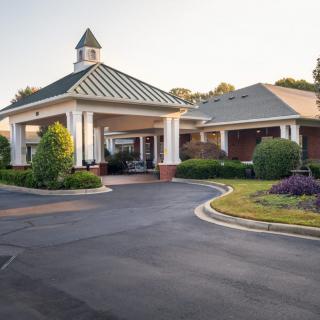 A welcoming entrance to a neatly landscaped building with a drive-through portico.