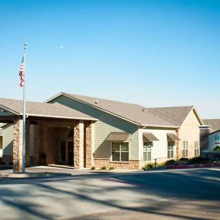 A modern building with a prominent entrance and an American flag flying outside on a sunny day.