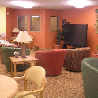 A cozy lounge area with colorful chairs, a large television, and soft lighting.