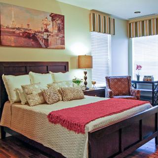A cozy bedroom with a neatly made bed, decorative pillows, and warm lighting.