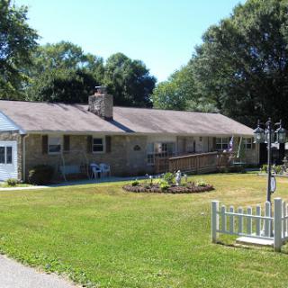 A charming single-story house with a manicured lawn and garden, set in a peaceful suburban environment.
