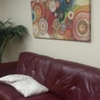 A cozy living room with a red couch, decorative pillow, and colorful artwork on the wall.