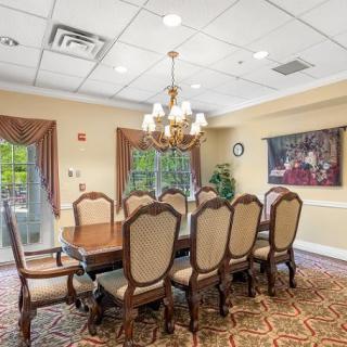 Elegant dining room with a chandelier, large wooden table, and upholstered chairs.