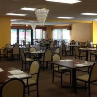 An empty restaurant dining area with neatly arranged tables and chairs, featuring a chandelier.