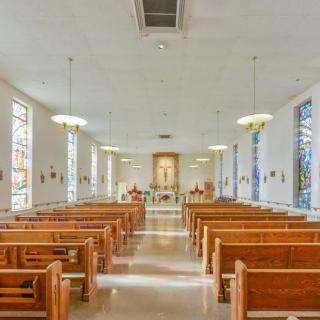 Interior of a church featuring wooden pews and an altar.