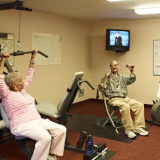 Seniors exercising in a gym with fitness equipment.