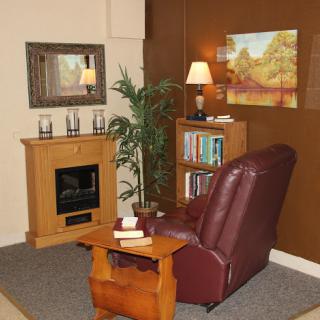 A cozy corner of a living room featuring a recliner, bookshelf, and decorative elements.