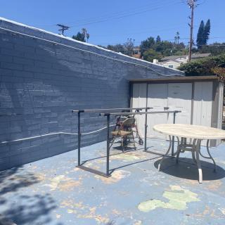 A sunny outdoor patio with a round table and some chairs, set against a painted wall.