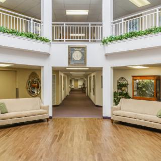 A spacious lobby with sofas, a clock, and decorative plants.
