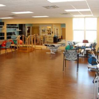 A spacious rehabilitation room equipped with various exercise and therapy equipment.