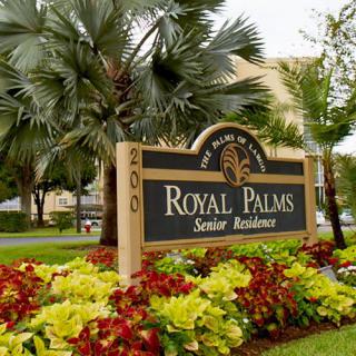 Entrance sign to Royal Palms Senior Residence surrounded by lush landscaping.