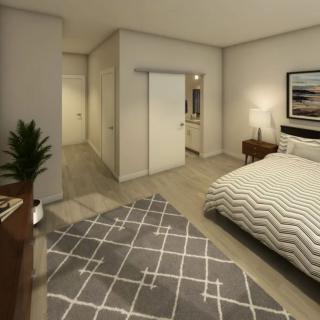 A modern bedroom with stylish decor, featuring a bed, nightstand, and a geometric rug.