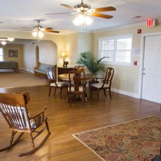 A cozy living space featuring a rocking chair, dining table, and ceiling fans.