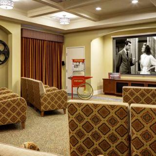 A cozy home theater setup with plush seating and a large projector screen displaying a black and white movie.