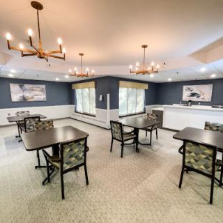 A spacious dining area with elegantly arranged tables and chairs, featuring modern chandeliers and a calm color palette.