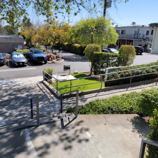 A sunny day in a landscaped area with a parking lot and well-maintained greenery.