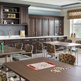 A well-organized kitchen and dining area featuring wooden cabinets, tables, and chairs with a game board setup.