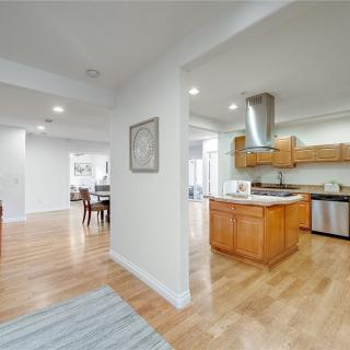 An open floor plan featuring a modern kitchen and dining area with hardwood floors and stainless steel appliances.