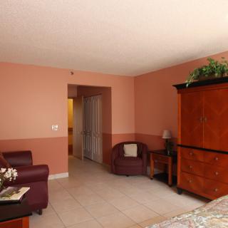 A hotel room interior with a warm color scheme, featuring an armchair and wooden furniture.