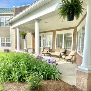 A cozy porch with seating, surrounded by a lush garden.