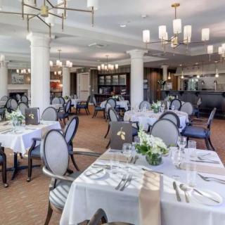An elegant and well-lit restaurant dining area with neatly arranged tables and chairs.