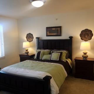 A cozy bedroom with a neatly made bed, two nightstands, and decorative lamps.