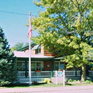 A quaint house with a porch, surrounded by trees and displaying an American flag.